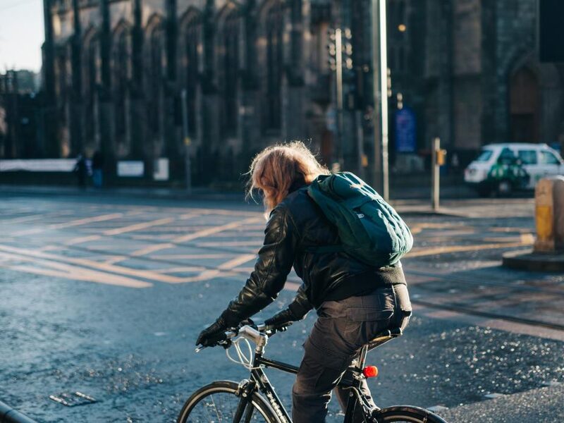 Cyclist on a city street in front of a stone building